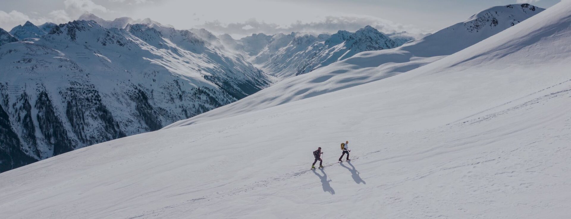 Two skiers enjoy Telemark skiing and free heel skiing on a snowy alpine slope.